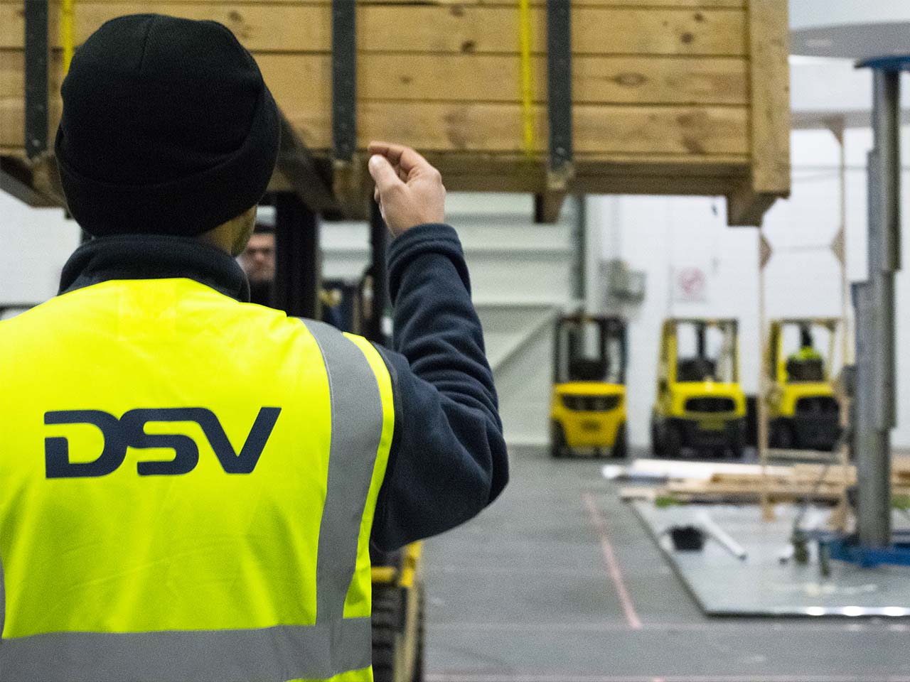 Male warehouse worker guiding a fork lift driver